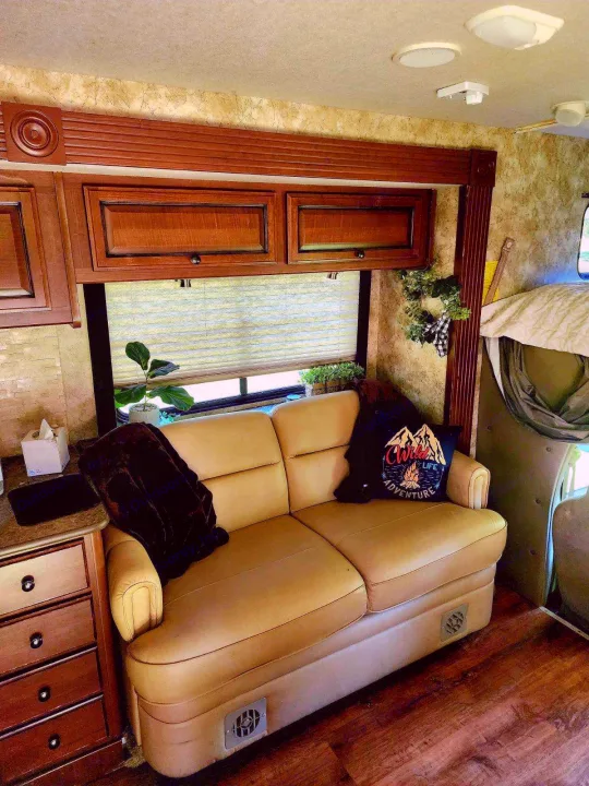 Comfortable RV rental interior with a cozy sofa, wooden cabinets, and window blinds. This inviting living space is ready for your adventure.. Tioga Ranger 2013