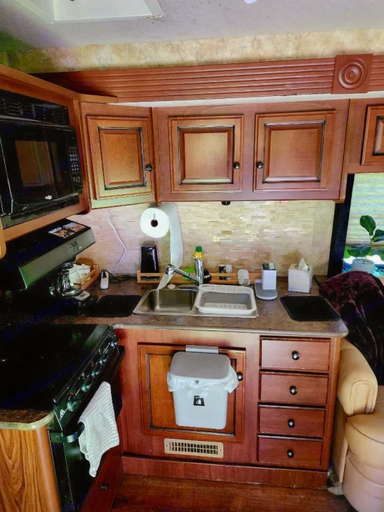 Inside this **rv rental** is a compact kitchen featuring a microwave, stove, sink, and storage for easy travel meals.. Tioga Ranger 2013