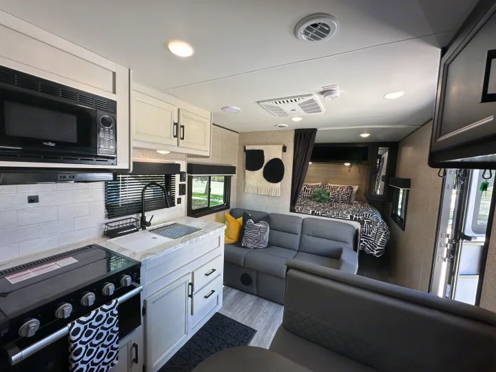Full view of a modern RV rental interior featuring a complete kitchen, comfortable living area, and private bedroom space.. Jayco Jay Flight SLX Baja Edition 2023