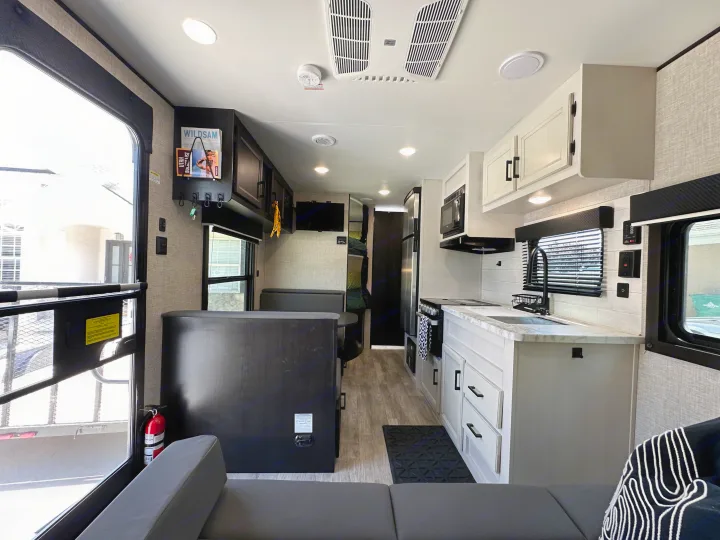 This modern RV rental features a well-equipped kitchen, comfortable living area with dark seating, and bunk beds, ideal for travel.. Jayco Jay Flight SLX Baja Edition 2023