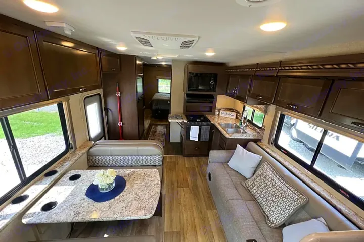 Modern rv rental interior with a comfy sofa, dinette, well-equipped kitchen, and a cozy bedroom in the back.. Thor Motor Coach Freedom Elite 2017