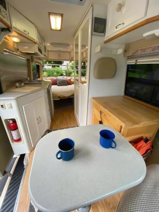 Enjoy the comfort of this rv rental! Full kitchen, dining area with mugs, and cozy bed for your travels.. Mercedes-Benz Sprinter 2005