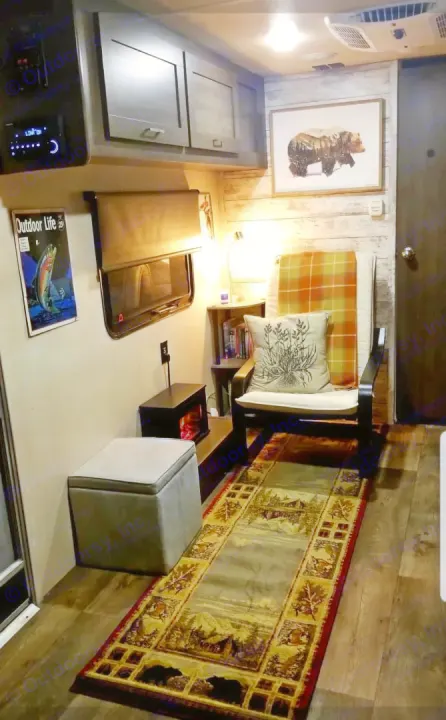 Spacious RV rental living area with a cozy armchair, mini fireplace, nature-themed rug, and entertainment unit.. Forest River Salem Cruise Lite 2018