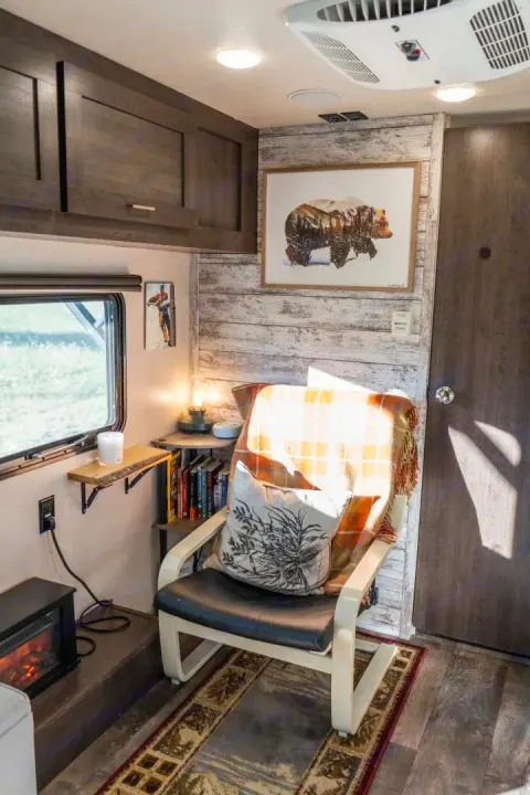 Inside a charming RV rental: rustic wood accent wall, comfy armchair, and fireplace make for a cozy travel retreat.. Forest River Salem Cruise Lite 2018