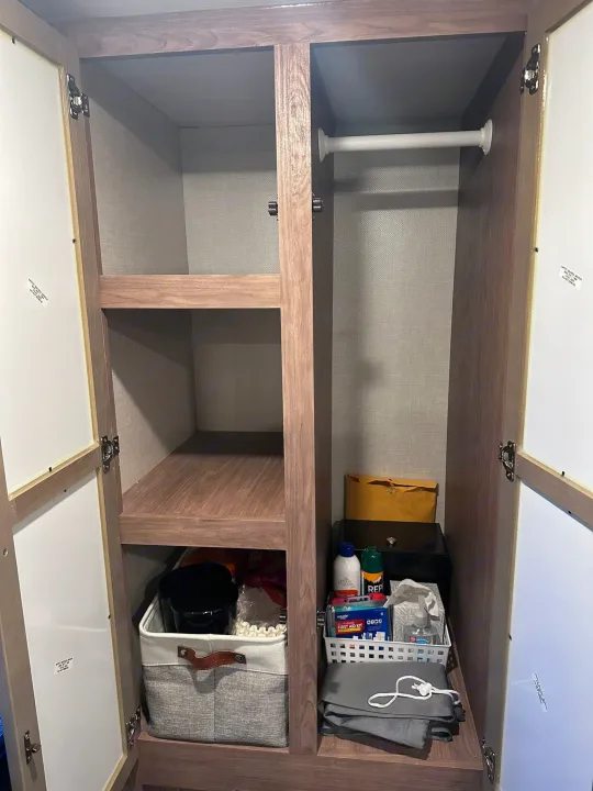 Organized RV rental closet: shelves, a hanging rod, and essential items like first aid, toiletries, and storage bins.. No Boundaries 19 2023