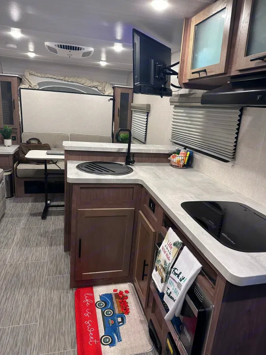 Spacious rv rental interior showing a full kitchen, dining area, and bed in the back. Perfect for travel.. No Boundaries 19 2023