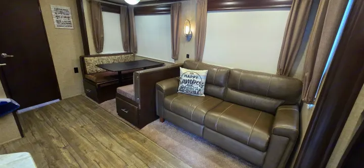 This RV rental living space includes a comfy sofa, dinette with bench seating, & wood floors. Enjoy your camping trip!. Forest River Cherokee Arctic Wolf 2018