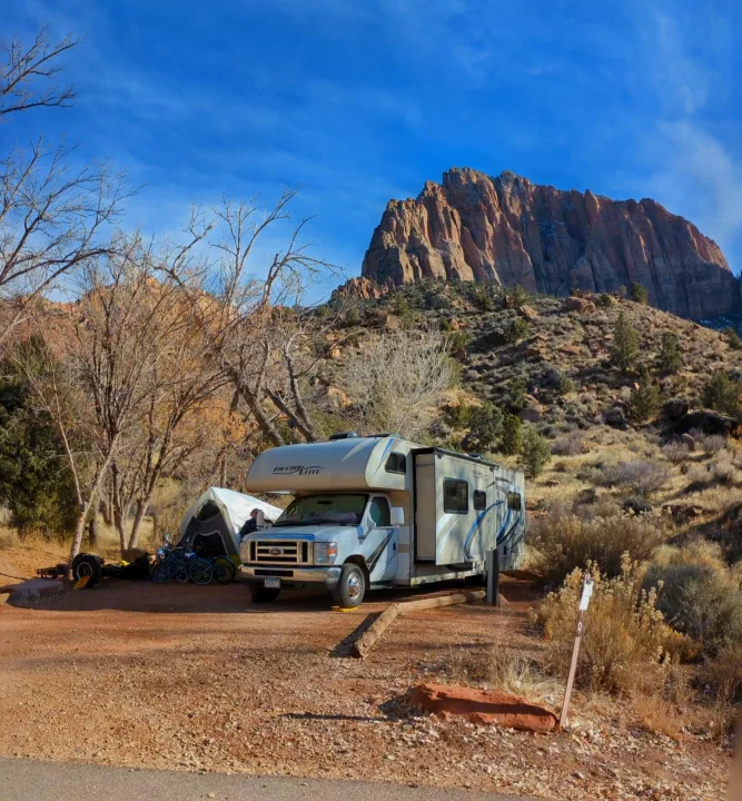 Freedom Elite RV rental parked at a rocky desert campsite (site 9) with a tent, bikes, and majestic mountains.. Thor Freedom Elite 2018