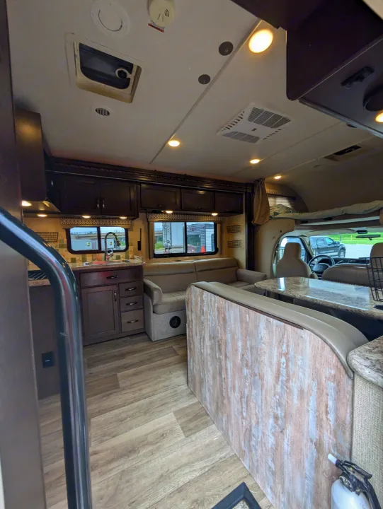 Bright rv rental interior featuring a modern kitchen, comfortable living area with dinette, and a cozy cab-over bed.. Thor Freedom Elite 2018