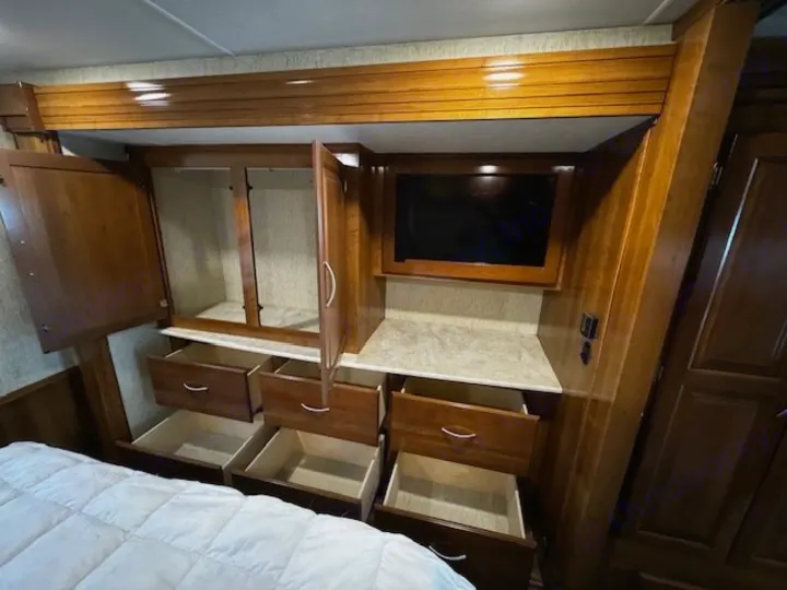 This rv rental offers smart bedroom storage: an open closet, TV, and many accessible pull-out drawers above the bed.. Coachmen Mirada 2018