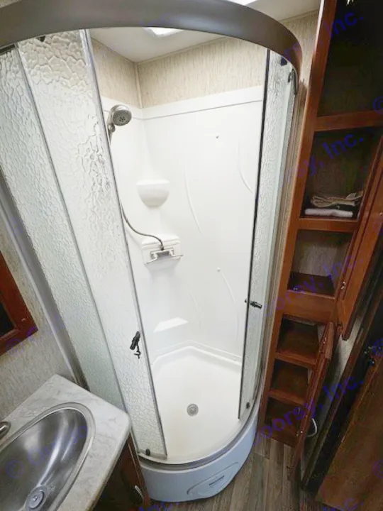 Inside an RV rental: a clean, compact bathroom with corner shower, vanity sink, and ample storage.. Coachmen Mirada 2018
