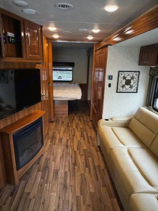 Explore this **rv rental**! A spacious interior shows a living room with a beige sofa, TV, fireplace, and a full-size bed in the rear bedroom.. Coachmen Mirada 2018