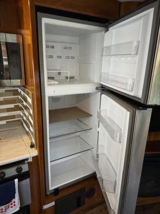 Clean, empty two-door refrigerator and freezer in an RV rental kitchen, ready for your adventures.. Coachmen Mirada 2018