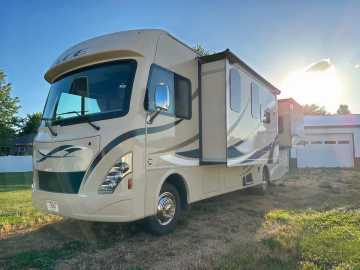 Spacious cream-colored RV rental with extended slide-out and awning, parked outdoors on a bright day. Ready for adventure!. Thor A.C.E. 2017