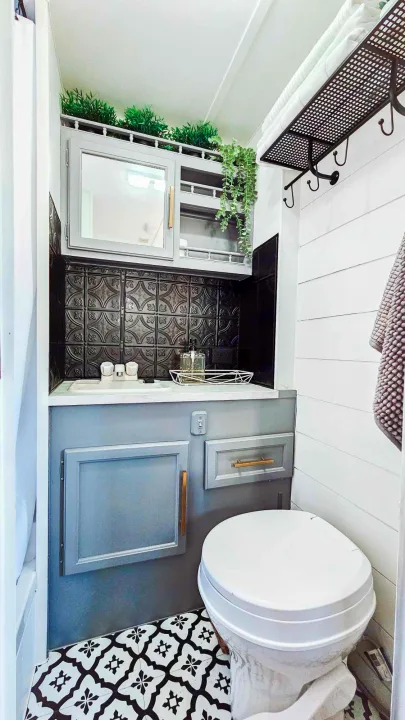 This stylish RV rental bathroom features gray cabinets, black embossed backsplash, white toilet, and patterned floor, optimized for small spaces.. Terry Fleetwood 1991