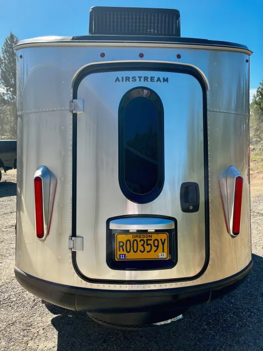 Rear of a shining silver Airstream travel trailer, ready for your next rv rental camping trip. Oregon plate R00359Y.. Airstream Base Camp 2021