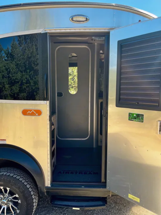 Open door of a silver Airstream Basecamp X RV, revealing its compact interior for your next rv rental.. Airstream Base Camp 2021