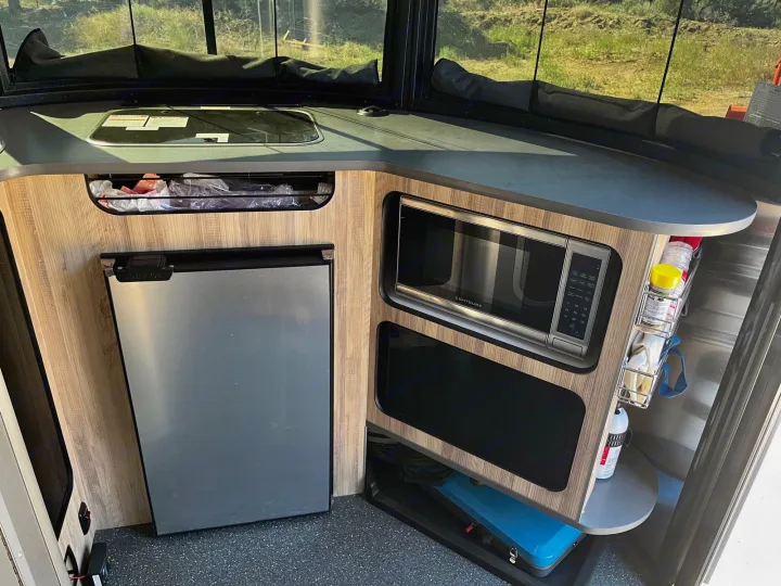 RV rental: Corner kitchen galley with built-in microwave, compact fridge, and cooktop for convenient travel.. Airstream Base Camp 2021