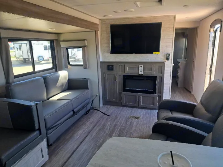Experience this modern RV rental interior featuring a sofa, recliners, and TV/fireplace unit, offering cozy comfort on the road.. Forest River Aurora Aurora 2024