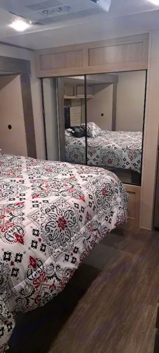 This inviting RV rental bedroom features a comfy bed with a stylish patterned comforter and mirrored wardrobe.. Forest River Aurora Aurora 2024