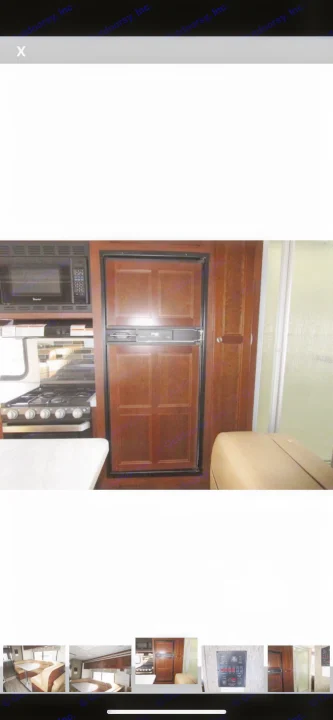 Inside an RV rental: full kitchen with microwave, stove, paneled refrigerator, and nearby shower. Dark wood cabinetry.. Forest River Sunseeker 2018