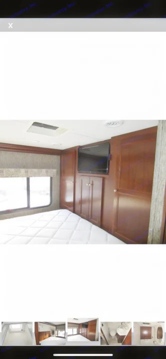 Inside an RV rental: a cozy bedroom awaits with a comfy bed, wall-mounted TV, and dark wood storage.. Forest River Sunseeker 2018