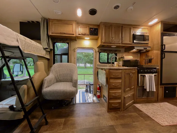 Spacious RV rental interior: well-lit kitchen with appliances, comfortable bunk over cab, and front living area. Ready for adventure!. Gulf Stream Conquest 2017