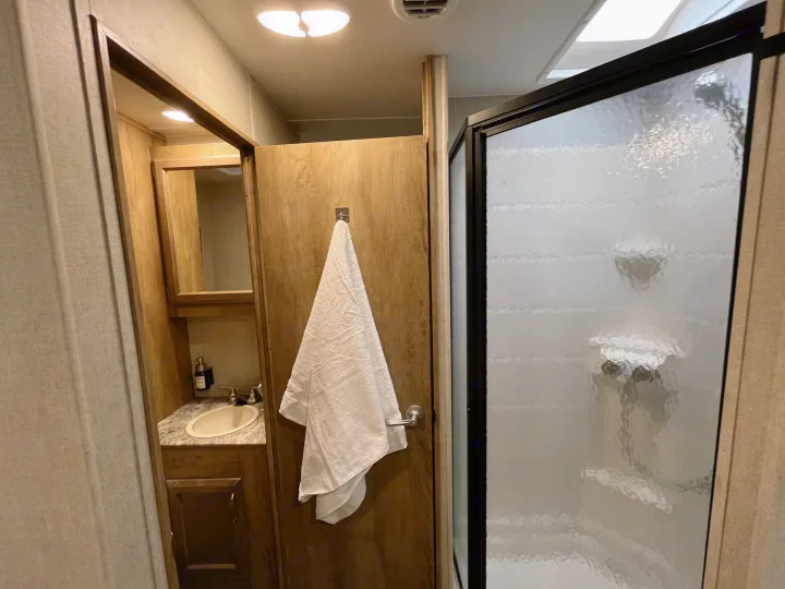 Compact RV rental bathroom with vanity, sink, and frosted shower. Ideal for travel comfort.. Gulf Stream Conquest 2017