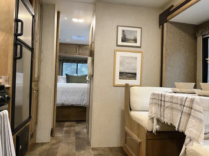 Step inside this cozy rv rental, showcasing a modern dining area, a glimpse of the kitchen, and a bedroom beyond.. Gulf Stream Conquest 2017