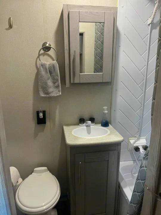 RV rental compact bathroom: a gray vanity with a sink, toilet, and stand-up shower with herringbone walls.. Keystone RV Fuzion Impact Toy Hauler 2022