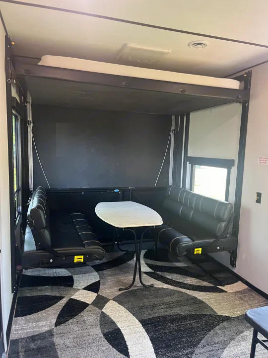 Spacious RV rental interior with convertible dinette, overhead bunk bed, and stylish patterned carpet.. Keystone RV Fuzion Impact Toy Hauler 2022