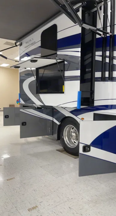 Explore a spacious blue and white luxury RV, featuring an open side, extended awning, and exterior TV. Great for rv rental trips!. Holiday Rambler Nautica 2022