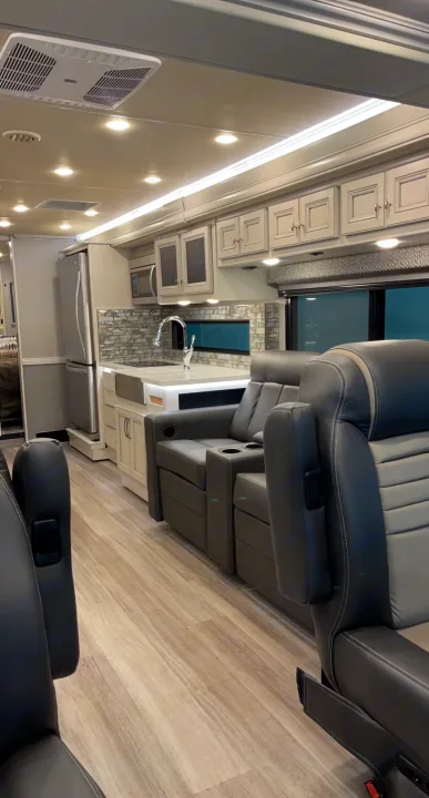 Inside a spacious rv rental: a modern kitchen with light cabinets, fridge, and cozy recliners for comfortable travel adventures.. Holiday Rambler Nautica 2022