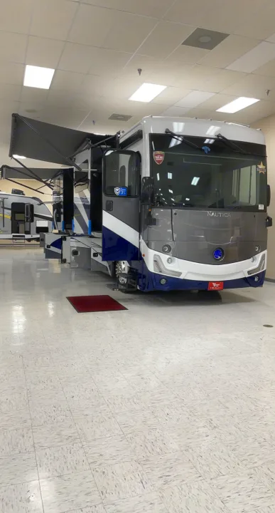 A striking grey and blue motorhome is showcased indoors with slide-outs extended, ready for an exciting rv rental journey.. Holiday Rambler Nautica 2022