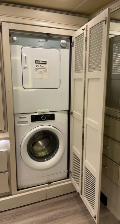 Inside an RV rental: a compact, stacked Whirlpool washer and dryer unit, offering laundry convenience on the go.. Holiday Rambler Nautica 2022