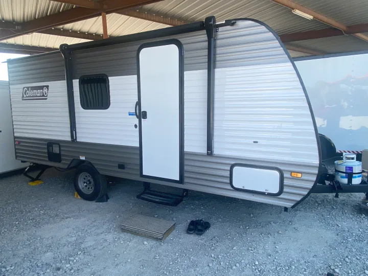 This grey and white Coleman RV rental, a travel trailer, is parked on gravel, ready for camping adventures.. Coleman Lantern LT 17b 2024