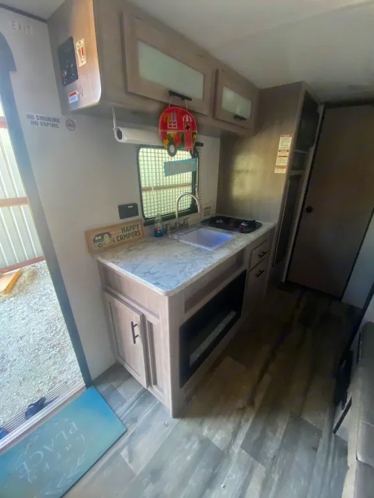 Step into this inviting rv rental! Featuring a compact kitchen with sink, stovetop, and an electric fireplace for comfort.. Coleman Lantern LT 17b 2024
