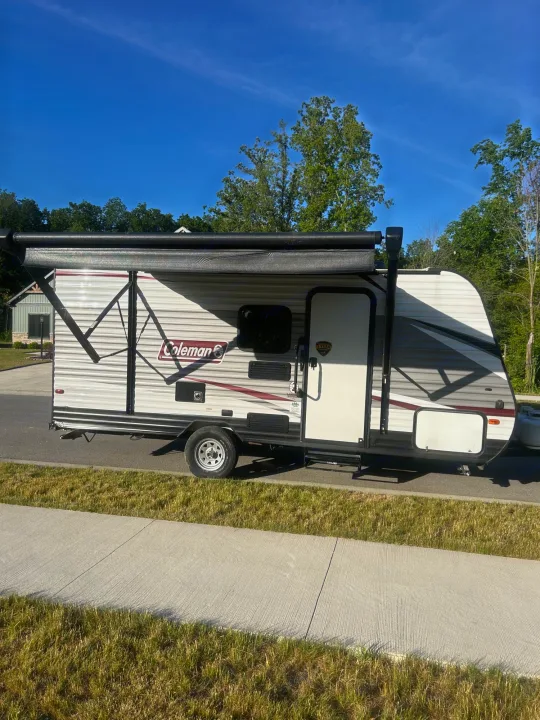 A Coleman travel trailer, perfect for an RV rental, parked on a sunny day with its awning deployed.. Coleman Lantern 17FQ 2020