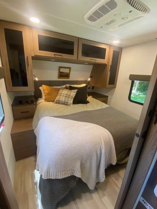 Step into this modern RV rental bedroom, complete with a cozy bed, ample storage cabinets, and essential AC unit.. Alliance Delta 251BH 2024