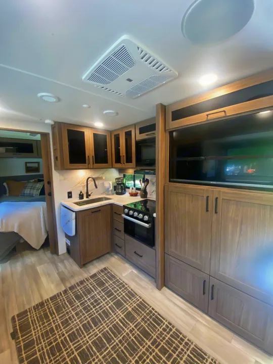 Modern RV rental interior: kitchen, entertainment center with TV, and cozy bedroom for comfortable travel.. Alliance Delta 251BH 2024