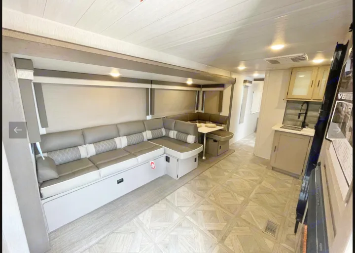 This modern RV rental interior offers a spacious living area with a U-shaped dinette and kitchen.. Forest River Wildwood Platinum 2024