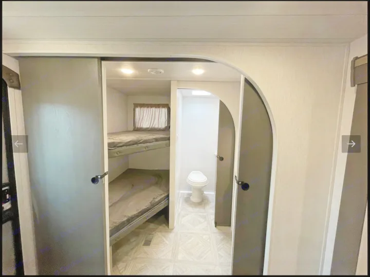 Explore this RV rental's clever layout: cozy bunk beds on the left, private toilet/bath area on the right.. Forest River Wildwood Platinum 2024