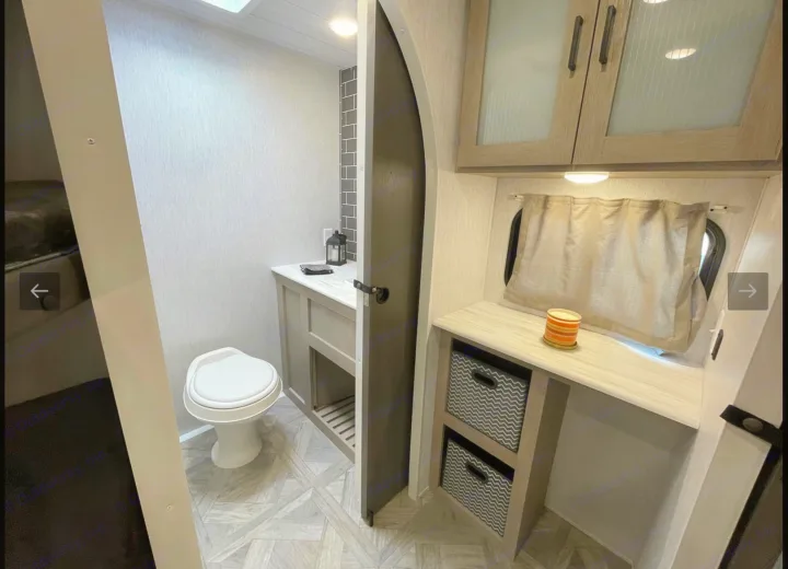 Clean RV rental bathroom & desk space with modern vanity, toilet, and organized storage.. Forest River Wildwood Platinum 2024
