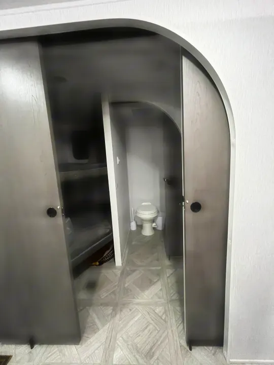 This RV rental features a compact bathroom with a toilet, visible past the bunk bed area, designed for efficient travel.. Forest River Wildwood Platinum 2024