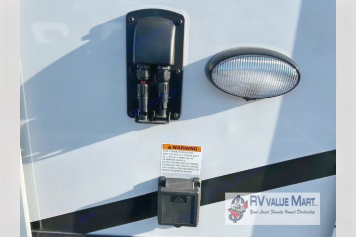 RV rental exterior: solar & 50-amp shore power connections, an exterior light, and an electrical warning label.. Forest River Palomino Solaire 2023
