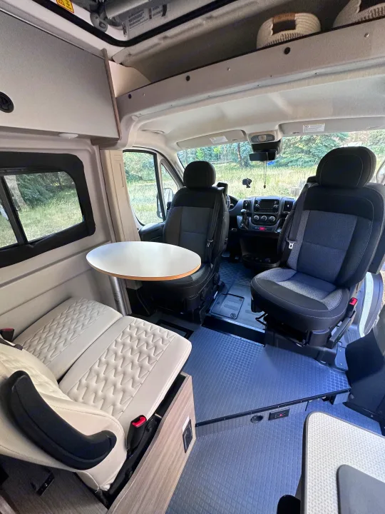Explore this RV rental's interior: driver's cockpit, swiveling front seats, round dining table, and a plush rear lounge.. Winnebago Solis 2022