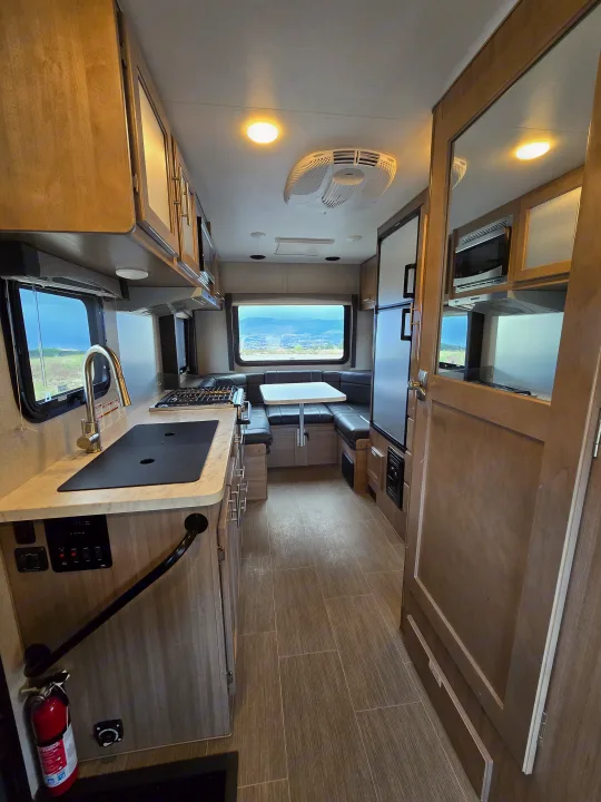 This inviting RV rental interior features a functional kitchen, comfortable dinette seating, and panoramic outdoor views.. ALP Adventurer 19RD 2021