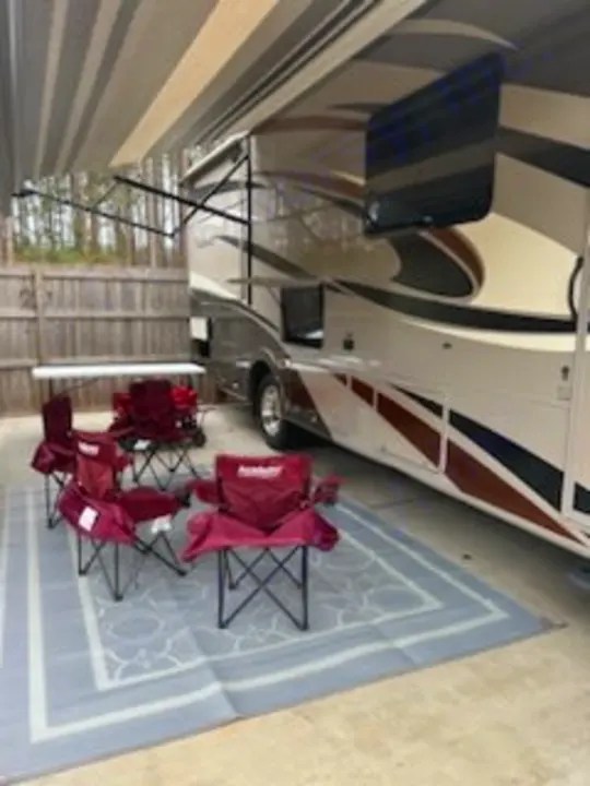 RV rental showing an outdoor living area with extended awning, TV, rug, and five folding chairs. Great for camping trips!. Forest River Coachmen Pursuit 2017