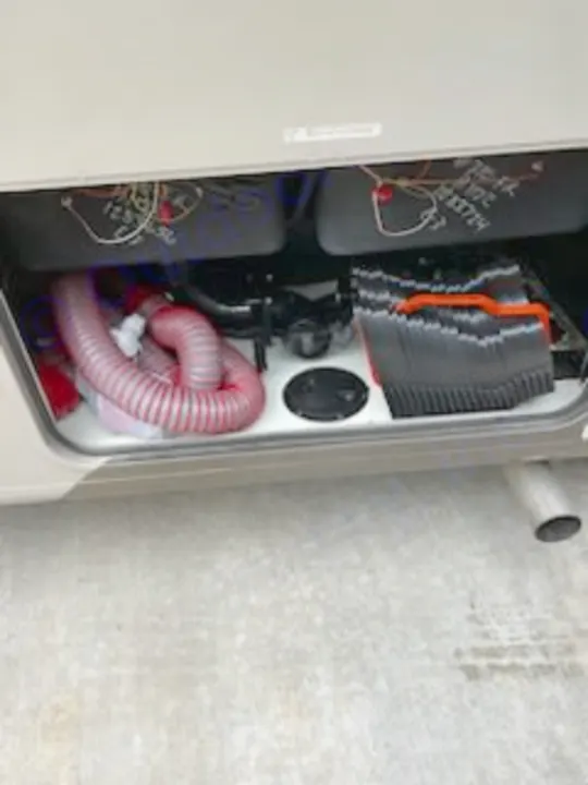 This RV rental's utility compartment holds a clear sewer hose and black leveling blocks, essential gear for your journey.. Forest River Coachmen Pursuit 2017