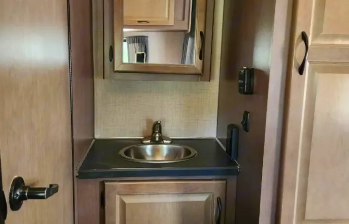 RV rental interior shows a compact bathroom vanity with a sink, faucet, mirrored cabinet, and wall-mounted controls.. Thor Majestic 2019